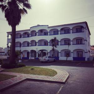un grand bâtiment avec une voiture garée devant lui dans l'établissement Hotel Eira Da Pedra, à Vila Nova de Milfontes