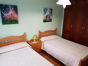 two beds in a bedroom with two lamps and pictures on the wall at Piso amplio en el centro de Vilagarcía de Arousa in Vilagarcia de Arousa