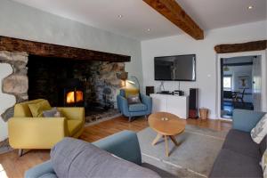 a living room with a couch and chairs and a fireplace at The Farmhouse Llyn Peninsula in Pistyll