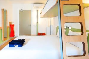 um quarto com uma cama branca e 2 janelas em ibis budget Gare de Poitiers em Poitiers