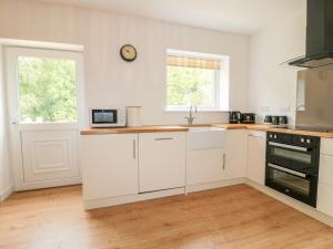 a kitchen with white cabinets and a clock on the wall at 7 Bogan in Eyemouth