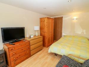 um quarto com uma cama e uma televisão numa cómoda em Lliwedd em Pwllheli