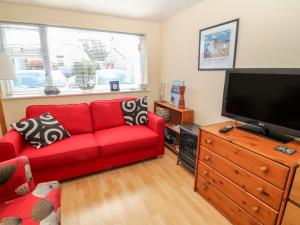 a living room with a red couch and a flat screen tv at Lliwedd in Pwllheli