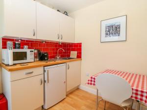 uma pequena cozinha com uma mesa e um micro-ondas em Lliwedd em Pwllheli