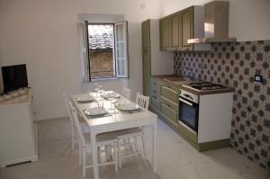 a kitchen with a white table with chairs and a stove at volterracentro in Volterra