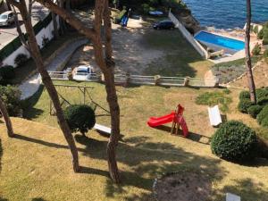 einen Spielplatz mit einer roten Rutsche neben dem Wasser in der Unterkunft Senya salvi 12 in Sant Feliu de Guixols