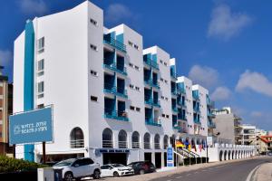 a white building with cars parked in front of it at THE FOZ Beach Hotel in Figueira da Foz
