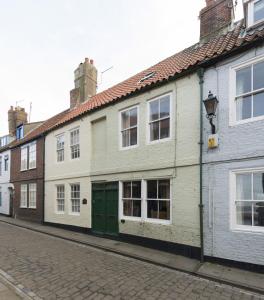 a white building with a green door on a street at Cobbles House in Whitby
