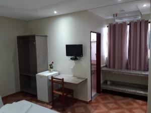a living room with a desk and a tv on the wall at Hotel Litoral in Aracaju