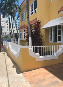 a yellow house with a white fence and palm trees at Hotel Villa del Sol in San Juan