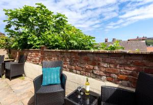 eine Terrasse mit Stühlen und einem Tisch mit einer Flasche Wein in der Unterkunft Fishermans Warehouse in Whitby