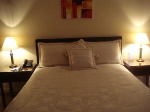 a bedroom with a bed with two lamps and a phone at Apartamentos Santa Maria in Bogotá