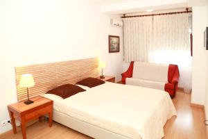 a bedroom with a white bed and a red chair at Casa Encantada - Poeta in Lisbon