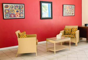 a room with chairs and a table and a red wall at Bay Gardens Inn in Gros Islet