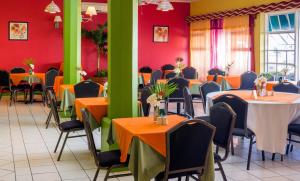 una sala da pranzo con tavoli, sedie e pareti rosse di Bay Gardens Inn a Gros Islet