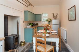 a kitchen with blue cabinets and a table and a refrigerator at Manor Cottage in Whitby