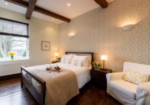 a bedroom with a large bed and a white chair at Mews Cottage in Whitby