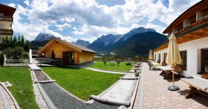 a resort with a patio with a view of mountains at Biovita Hotel Alpi in Sesto