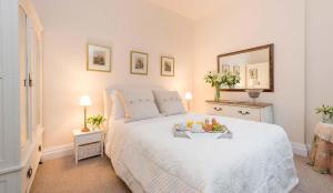 Dormitorio con cama blanca y bandeja de fruta. en Manor Cottage en Whitby