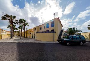 une voiture garée devant un immeuble avec des palmiers dans l'établissement Porto Santo Blue House, à Porto Santo