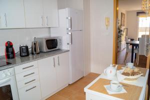 a kitchen with white cabinets and a microwave at Porto Santo Blue House in Porto Santo