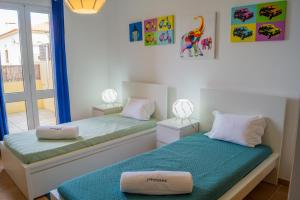 two twin beds in a room with a window at Porto Santo Blue House in Porto Santo
