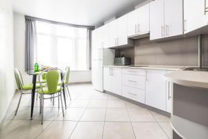 una cocina con armarios blancos y una mesa con sillas verdes en Apartments Roksolany 16, en Truskavets