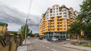 a large yellow building on a city street with cars at Apartments Roksolany 16 in Truskavets