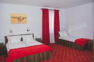 a hotel room with two beds with red sheets at Pensiunea Iliada in Sibiu