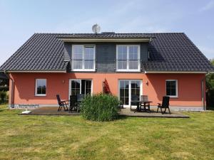 uma casa com cadeiras e uma mesa em frente em La Mer - Ferienwohnungen em Bresewitz