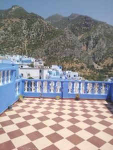 a blue balcony with a checkered floor and mountains at Maison Bahija in Chefchaouen