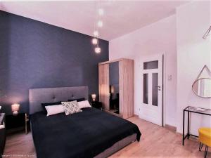 a bedroom with a large black bed with pink pillows at Apartament Nad Jeziorem Czos in Mrągowo