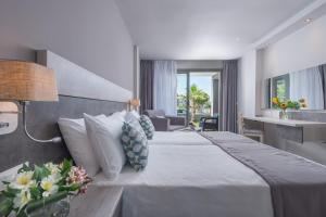 a hotel room with a large bed and a desk at Dionysos Hotel & Suites in Hanioti