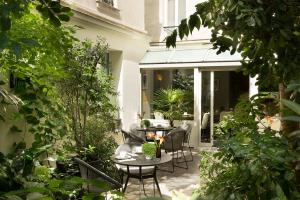 a patio with tables and chairs and plants at Hôtel A La Villa des Artistes in Paris