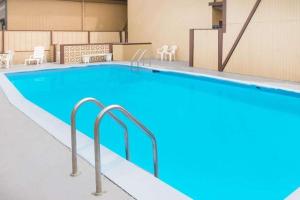 a large swimming pool in a building with chairs at Travelodge by Wyndham Terre Haute in Terre Haute