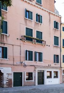 ヴェネツィアにあるPrince Apartmentsのピンクの建物(窓、バルコニー付)