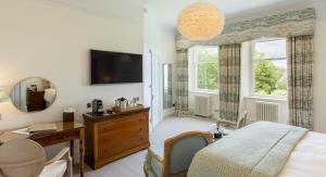 a bedroom with a bed and a desk and a mirror at Lindeth Fell Country House in Bowness-on-Windermere