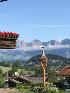 un poste con una cruz en la cima de una ciudad con montañas en Pension Feiersinger en Kitzbühel
