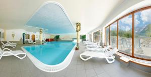 a pool in a hotel with chairs and a swimming pool at Biovita Hotel Alpi in Sesto