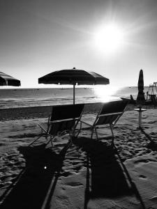 due sedie e un ombrellone su una spiaggia di Hotel Villa Joseph a Marotta