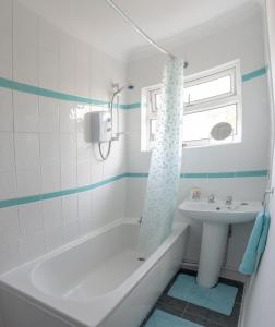 a bathroom with a white tub and a sink at Cwtch Y Coetir in Swansea