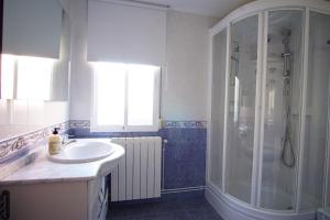 a white bathroom with a shower and a sink at LA CASA DEL MONTE in Granja Llumes
