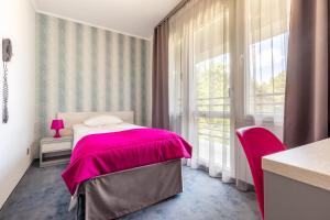 a bedroom with a pink bed and a window at Hotel Perłowy in Okuninka