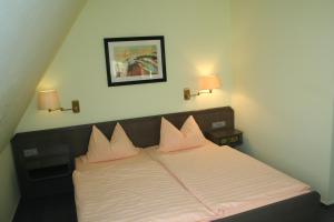 a bedroom with a bed with pink pillows on it at Hotel & Restaurant Dortmunder Eck in Horn-Bad Meinberg