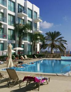 a large swimming pool with chairs and a building at Coralli Superior Seaview in Protaras