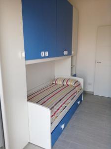 un piccolo letto in una stanza con armadi blu di appartamento sapore di mare a Pozzallo