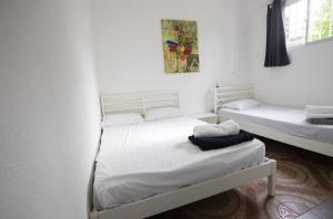 two beds in a room with white walls at Whostal in Santiago de los Caballeros
