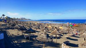 a beach with many umbrellas and people on the sand at 100 meters from the ocean in Callao Salvaje +29 photos
