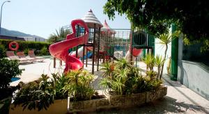 un parque infantil con un tobogán rojo en un parque en Hotel Europa, en Alfaz del Pi