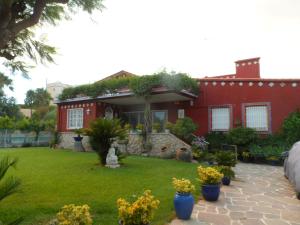 a red house with a green yard with flowers at Apartamento con terraza y vistas al mar in Burriana